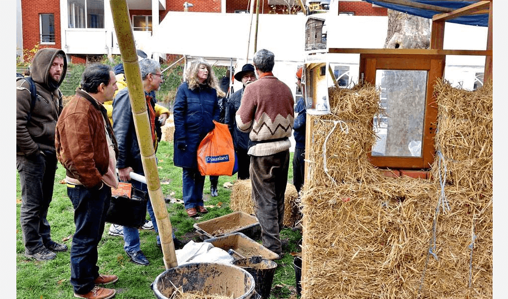 Personnes devant une botte de foin et des outils lors du Village Mondial des Alternatives