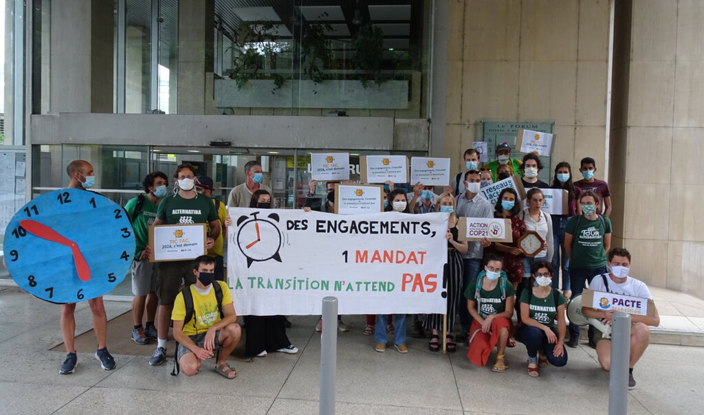 Des activistes tenant des affiches, par exemple "Des engagements, un mandat : la transition n'attend pas", une horloge en carton